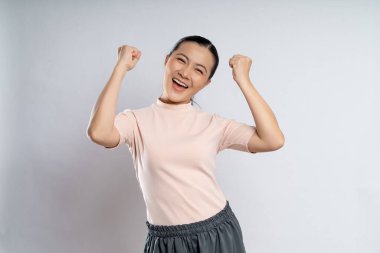 Asian woman happy confident showing her fist make a winning gesture standing isolated on white background.