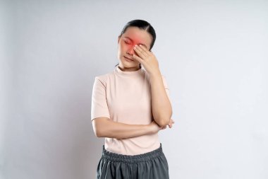 Asian woman was sick with eyes pain, irritate itching and touching her eyes with red spot standing isolated on white background.