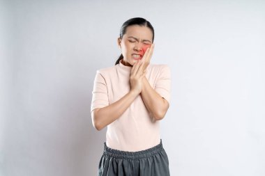 Asian woman was sick with toothache touching her cheek with red point and standing isolated on white background.