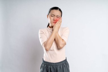 Asian woman was sick with toothache touching her cheek with red point and standing isolated on white background.