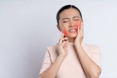 Asian woman was sick with toothache touching her cheek with red point and standing isolated on white background.