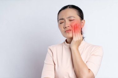 Asian woman was sick with toothache touching her cheek with red point and standing isolated on white background.