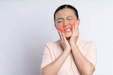 Asian woman was sick with toothache touching her cheek with red point and standing isolated on white background.