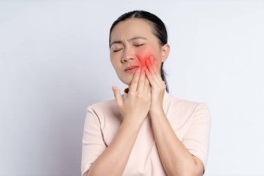 Asian woman was sick with toothache touching her cheek with red point and standing isolated on white background.