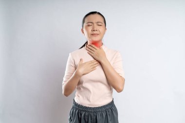 Asian woman was sick with sore throat, coughing sneezing and touching neck with red spot, standing isolated on white background.