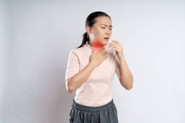 Asian woman was sick with sore throat, coughing sneezing and touching neck with red spot, standing isolated on white background.