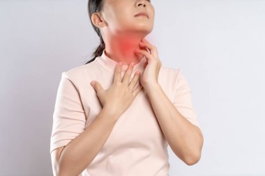 Asian woman was sick with sore throat, coughing sneezing and touching neck with red spot, standing isolated on white background.