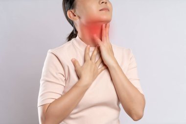 Asian woman was sick with sore throat, coughing sneezing and touching neck with red spot, standing isolated on white background.