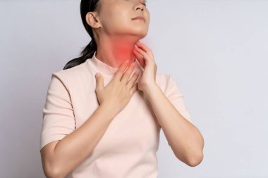 Asian woman was sick with sore throat, coughing sneezing and touching neck with red spot, standing isolated on white background.