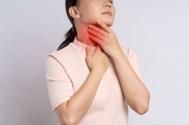 Asian woman was sick with sore throat, coughing sneezing and touching neck with red spot, standing isolated on white background.
