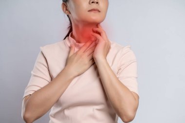 Asian woman was sick with sore throat, coughing sneezing and touching neck with red spot, standing isolated on white background.