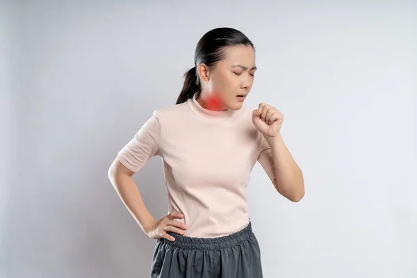 Asian woman was sick with sore throat, coughing sneezing and touching neck with red spot, standing isolated on white background.