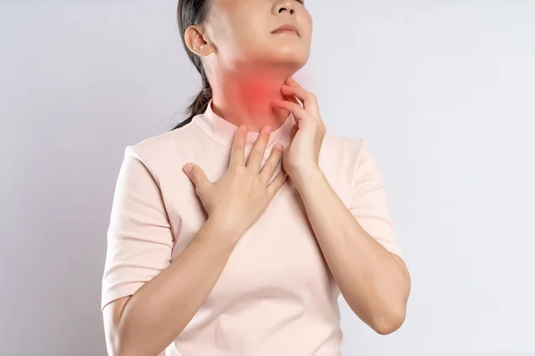 Asian woman was sick with sore throat, coughing sneezing and touching neck with red spot, standing isolated on white background.