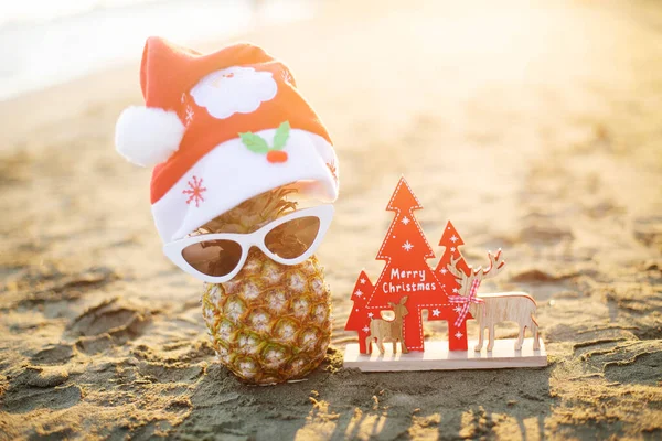 夕日のビーチでサングラスとクリスマスの装飾が施されたパイナップル クリスマス休暇のコンセプト — ストック写真