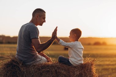Baba ve oğul gün batımında parkta oynuyorlar. Aile, güven, koruma, bakım, ebeveynlik, yaz tatili konsepti