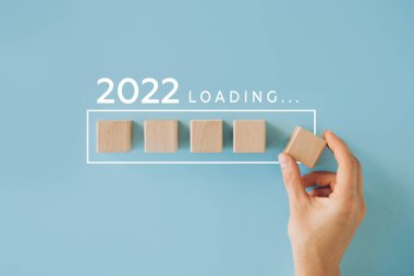 Kadın eli 2022 'ye geri sayım için tahta küp koyuyor. 2021 'den 2022' ye kadar yükleme yılı. Yeni yıl başlangıcı konsepti