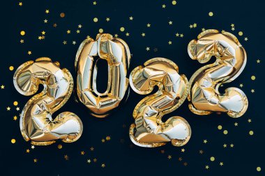 Mutlu yıllar ve Noel tatili konsepti 2022. Siyah arka planda parıldayan yıldızlı altın balonlar. Hediye çeki. Üst yatay görünüm