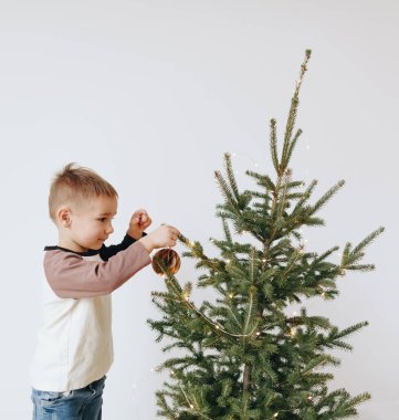 Evde Noel ağacı süsleyen çocuk. Küçük çocuk kış tatilini kutluyor