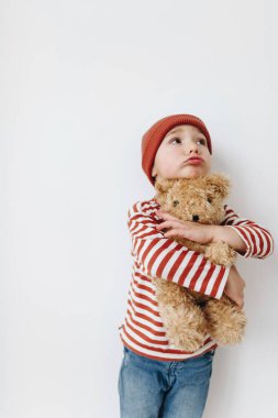Beyaz arka planda oyuncak ayısı olan küçük çocuk.