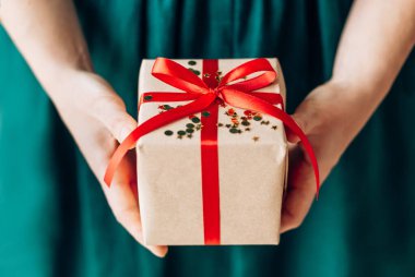 Kırmızı kurdeleli mutlu noel hediyesini tutan kadın, yeni yıl sürprizini hazırla neşeli el yapımı Noel hediyesi.