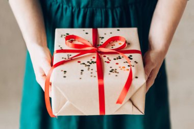 Kadın elleri kırmızı fiyonklu hediye kutusunu tutuyor. Noel tatiline hazırlanıyorum.