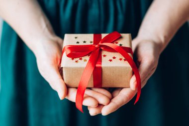 Kırmızı kurdeleli mutlu noel hediyesini tutan kadın, yeni yıl sürprizini hazırla neşeli el yapımı Noel hediyesi.