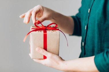 Kırmızı kurdeleli mutlu noel hediyesini tutan kadın, yeni yıl sürprizini hazırla neşeli el yapımı Noel hediyesi.