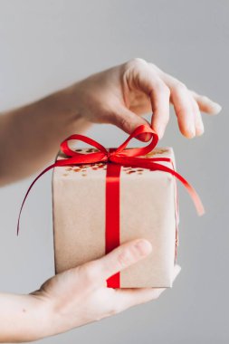 Kadın elleri kırmızı fiyonklu hediye kutusunu tutuyor. Noel tatiline hazırlanıyorum.