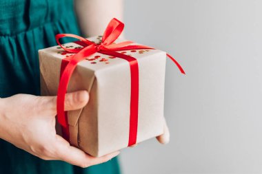 Kırmızı kurdeleli mutlu noel hediyesini tutan kadın, yeni yıl sürprizini hazırla neşeli el yapımı Noel hediyesi.