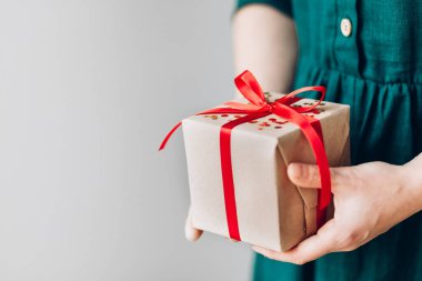 Kırmızı kurdeleli mutlu noel hediyesini tutan kadın, yeni yıl sürprizini hazırla neşeli el yapımı Noel hediyesi.