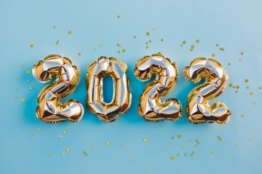 Mutlu yıllar ve Noel tatili konsepti 2022. Mavi arka planda parıldayan yıldızlı altın balonlar. Mesaj için yeri olan hediye kartı. Üst yatay görünüm