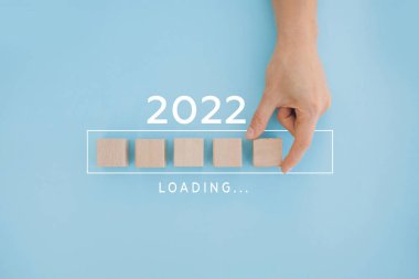 Kadın eli 2022 'ye geri sayım için tahta küp koyuyor. 2021 'den 2022' ye kadar yükleme yılı. Yeni yıl başlangıcı konsepti