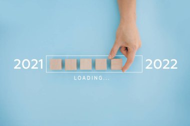 Kadın eli 2022 'ye geri sayım için tahta küp koyuyor. 2021 'den 2022' ye kadar yükleme yılı. Yeni yıl başlangıcı konsepti
