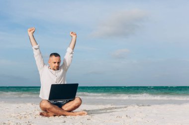 Sahilde dizüstü bilgisayar kullanan başarılı bir genç. Rahatlama Tatili Açık Sahil Konsepti