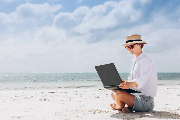 一个女人坐在美丽的热带海滩上 一边用笔记本电脑键盘打字 自由工作 远程工作 社会疏离 电子学习 创造性专业 新业务 满足在线概念 — 图库照片