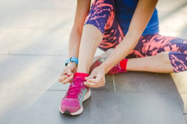 Spor salonundaki kadın ayakkabı bağcıklarını yolda bağlıyor. Şehrin sokaklarında spor ayakkabıları giymiş bir koşucu. Koşmadan önce ayakkabı bağı bağlayan aktif kadın