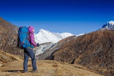 Arka planda Himalayalar 'ın güzel yaz manzaralı dağlarda yürüyüş yapan Sırt çantalı Kadın Gezgin. Everest Merkez Kampı yürüyüşü. Arka planda Cho oyu dağı var.