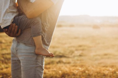 Father holding his son's little foot in an outdoor park. Lifestyle portrait