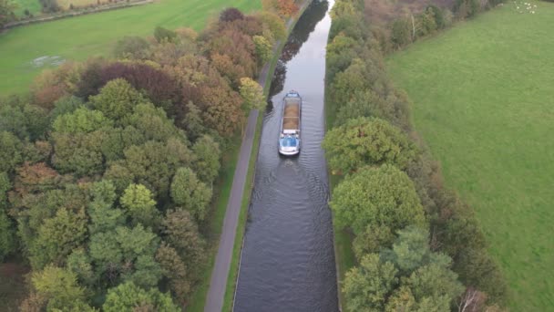 Luftaufnahme aus 4K Vogelperspektive mit einer Wasserstraßendrohne mit einem Lastkahn oder Frachtschiff, das über das natürliche grüne Erholungs- und Ackerland segelt — Stockvideo