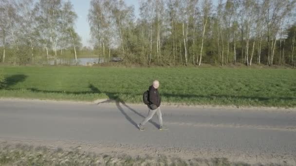 Spectaculaire luchtfoto van een man die tijdens zonsondergang wandelt in de velden van het Wilde platteland — Stockvideo