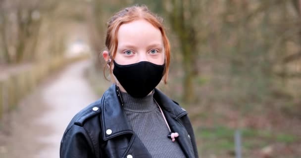 Schöne junge Mädchen oder Frauen tragen Gesichtsmasken, um sich vor Coronavirus Ausbruch der zweiten Welle der Pandemie zu schützen und schauen in die Kamera im Freien. Rotschopf Student zeigt Daumen nach oben aus nächster Nähe — Stockvideo