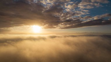 Hava görüntüsü. Sis içinde uçmak, güneşin doğuşundaki sabah bulutlarının üzerinde uçmak. Hava kamerası görüntüsü. Bulutların üzerinden güneşe doğru uçarken sis bulutları yüzüyor. Sisli hava