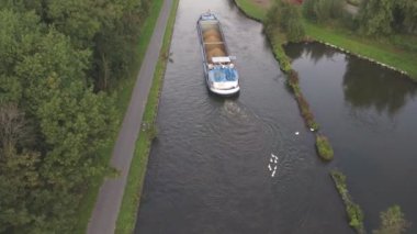 Rijkevorsel, Belçika, 29 09 2021, Aerial 4K hava aracı, mavna ya da yük gemisiyle doğal yeşil ormanlık ve çiftlik alanı boyunca yelken açan bir su yolu aracıyla vuruldu. 