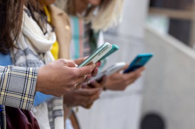 Çok ırklı bir grup genç kadın, şehrin dışındaki bir cep telefonu uygulamasını kullanarak ellerine odaklanıyor.