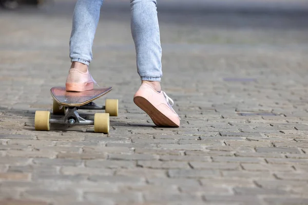 Vystřižený záběr mladé ženy nohy v teniskách praxe nové triky na skateboarding v parku. Sportovní a městský koncept životního stylu — Stock fotografie