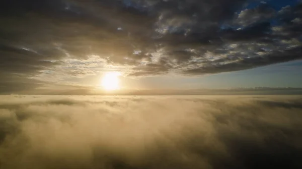 Vista aérea. Volando en la niebla, volar en la niebla sobre las nubes de la mañana temprano en el sol naciente. Cámara aérea grabada. Vuelo por encima de las nubes hacia el sol con las nubes de niebla flotando. Clima brumoso — Foto de Stock