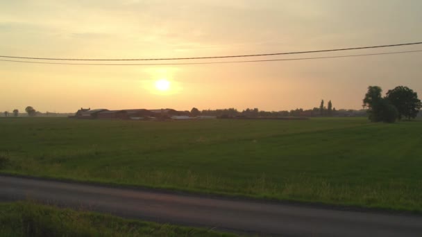 Zachód słońca nad farmą leśną na belgijskiej wsi, przelatujący obok drzew — Wideo stockowe