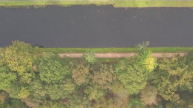 Sonbahar ormanlarında bir nehrin ya da kanalın insansız hava aracı tarafından tepeden aşağı bakılıyor.