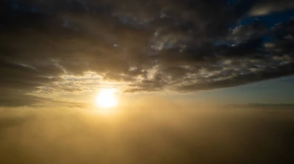 Widok z lotu ptaka. Latanie we mgle, latanie we mgle nad porannymi chmurami we wschodzącym słońcu. Zdjęcia z kamery lotniczej. Lot nad chmurami ku słońcu z chmurami mgły pływającymi obok. Mglista pogoda — Zdjęcie stockowe