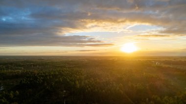 Yeşil çalıları ve renkli gökyüzü olan bir nehrin üzerinde güzel bir gün batımı.